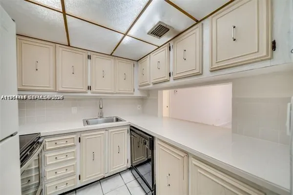 a kitchen with white cabinets and sink