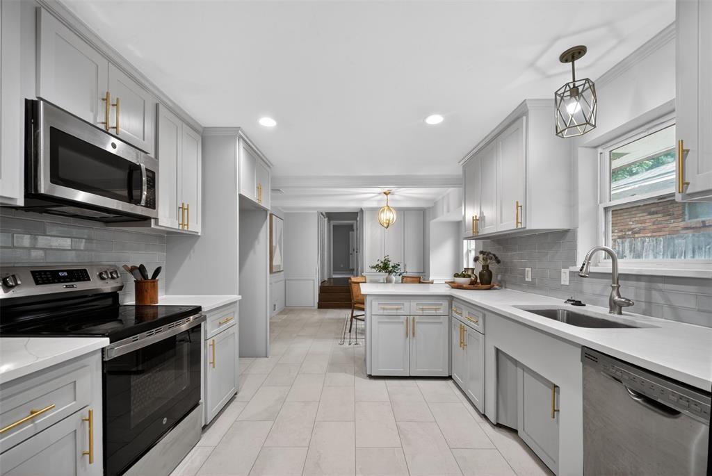 9660 Timberleaf Drive Dallas, TX 75243 - Photo 13 of 40 Spacious kitchen featuring light gray cabinetry with gold-tone hardware, stainless steel appliances, light-toned countertops, and a subway tile backsplash