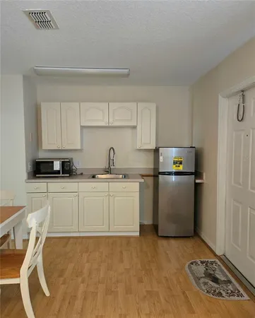 a kitchen with a refrigerator a stove top oven and white cabinets