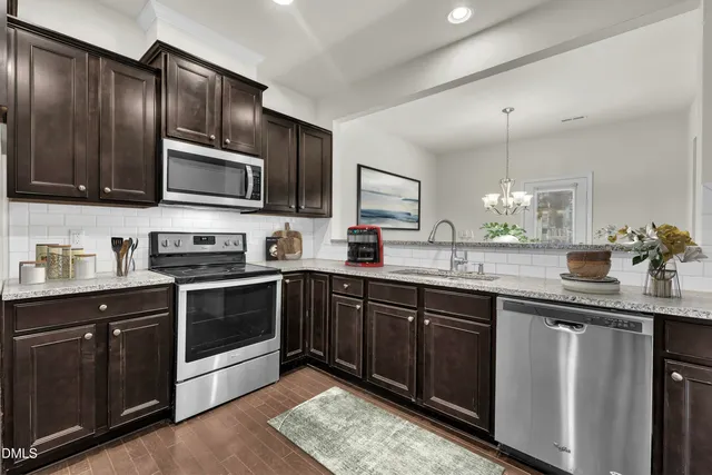 a kitchen with granite countertop wooden cabinets stainless steel appliances and a sink