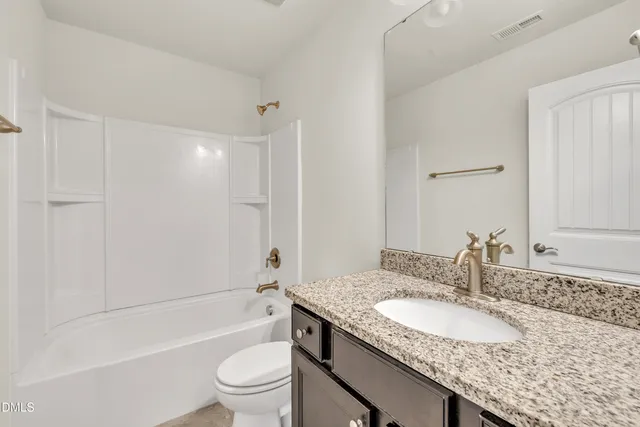 a bathroom with a granite countertop sink a toilet and shower