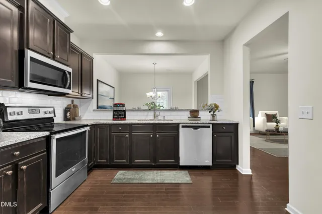 a large kitchen with stainless steel appliances granite countertop a stove top oven a sink dishwasher a microwave oven and a cabinets with wooden floor