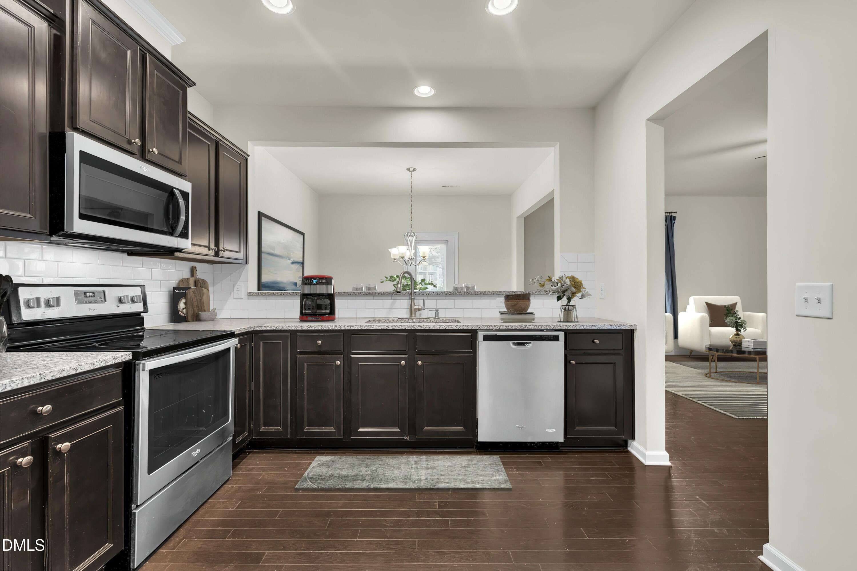 519 Brier Crossings Loop Durham, NC 27703 - Photo 10 of 36 a large kitchen with stainless steel appliances granite countertop a stove top oven a sink dishwasher a microwave oven and a cabinets with wooden floor