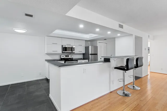 a kitchen with stainless steel appliances kitchen island granite countertop a refrigerator and microwave