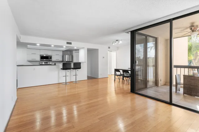 a view of empty room with wooden floor and kitchen view