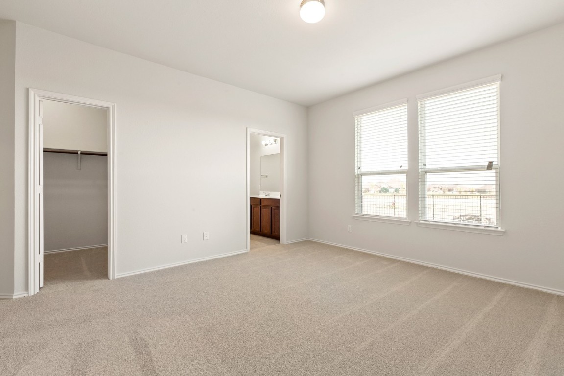 500 Martha Drive Buda, TX 78610 - Photo 5 of 7 Unfurnished bedroom with light colored carpet, a walk in closet, and connected bathroom