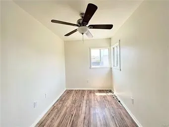 an empty room with wooden floor ceiling fan and windows