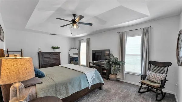 a bedroom with a bed a chair and potted plant on the dresser