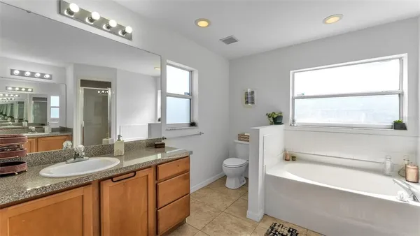 a bathroom with a granite countertop sink mirror vanity bathtub and a toilet