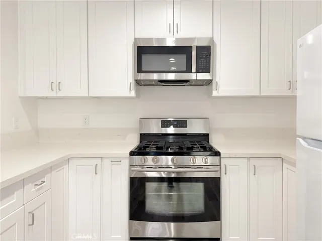 a kitchen with stainless steel appliances granite countertop white cabinets a stove top oven