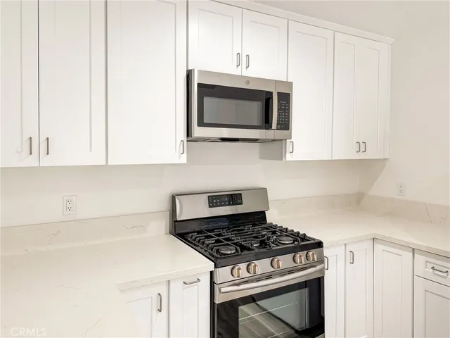 a kitchen with stainless steel appliances a white cabinet and a microwave
