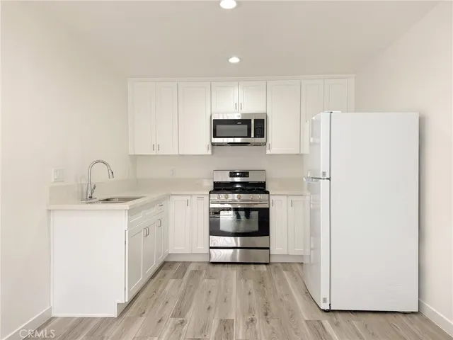 a kitchen with granite countertop a refrigerator stove and sink
