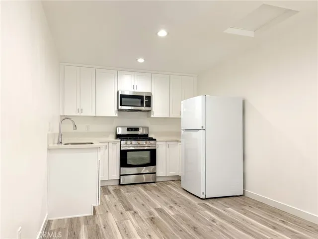 a kitchen with a refrigerator a stove top oven and white cabinets