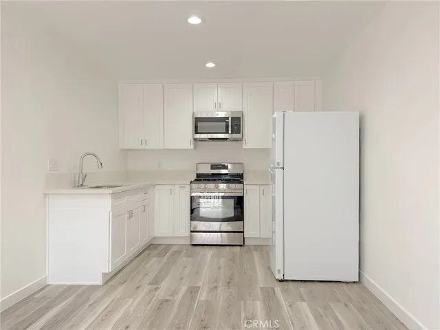 a kitchen with granite countertop a refrigerator stove and white cabinets