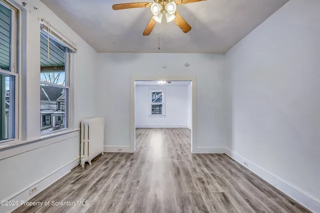 a view of empty room with wooden floor and fan