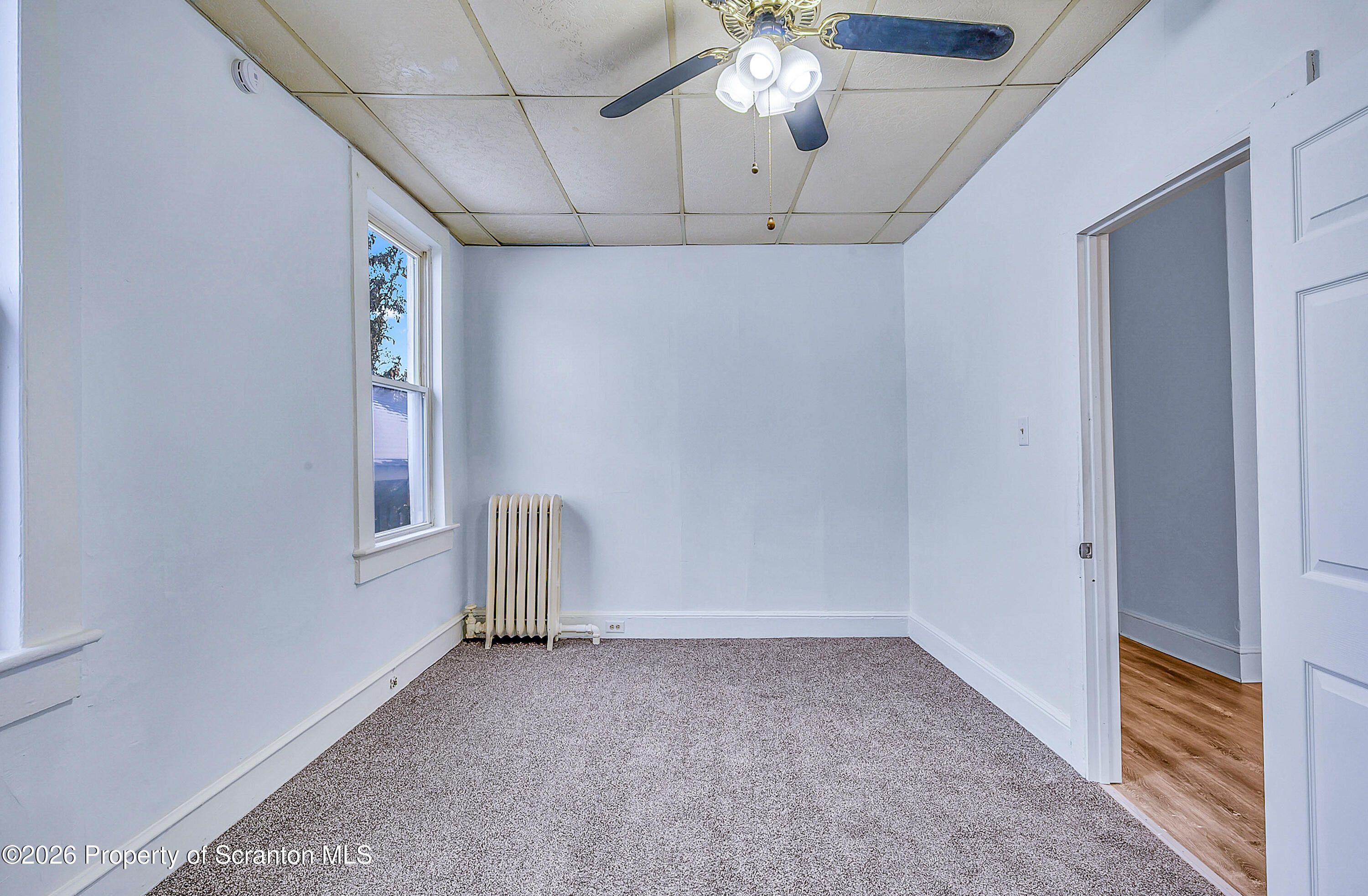 228 North Main Street Taylor, PA 18517 - Photo 14 of 19 en empty room with chandelier fan and windows