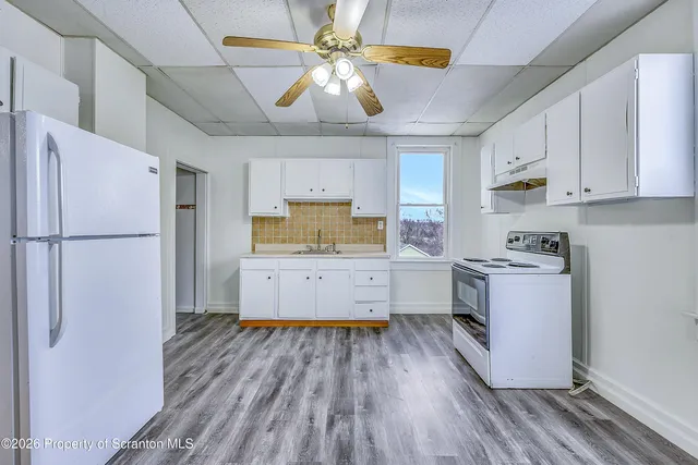 a kitchen with a refrigerator and white cabinets