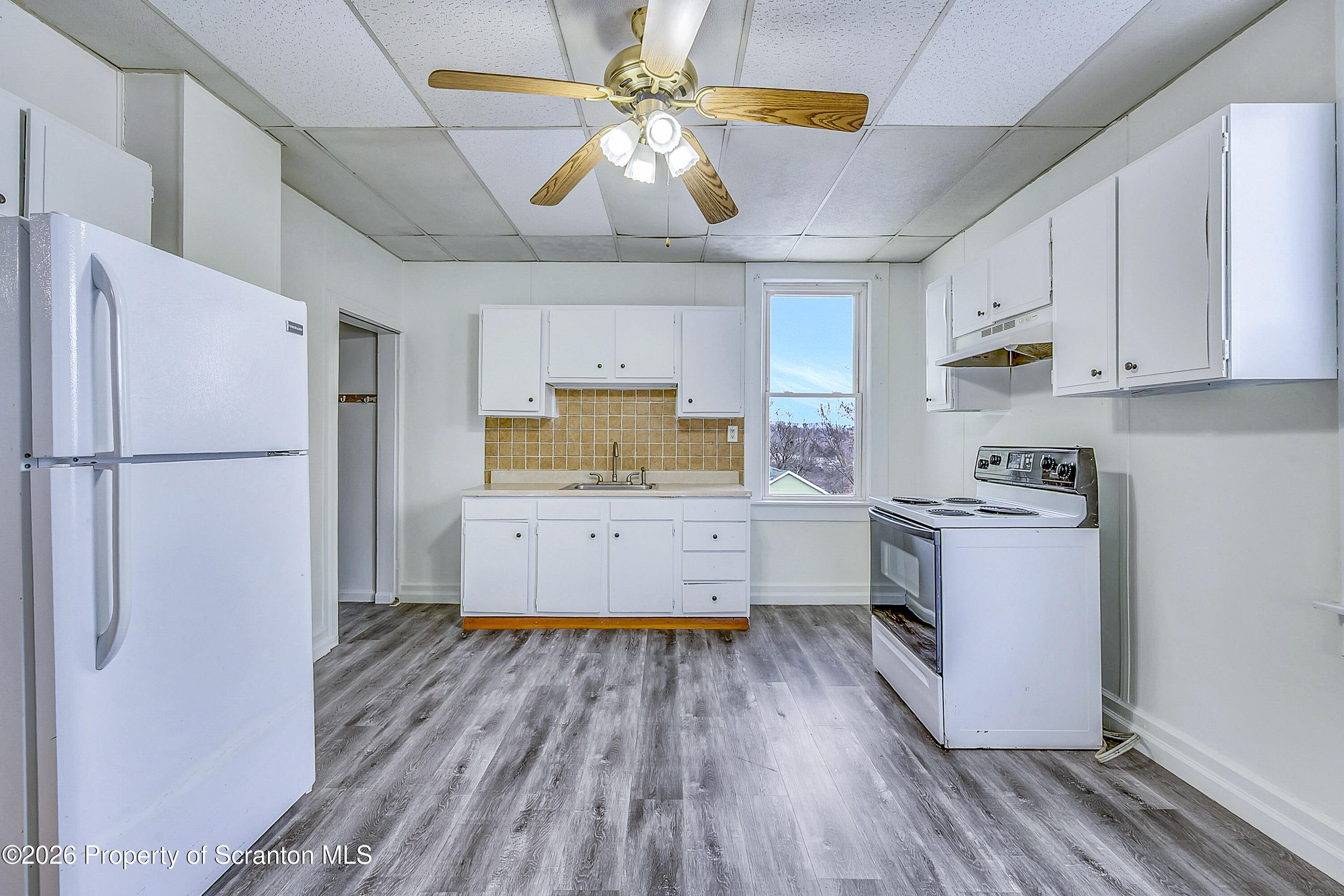 228 North Main Street Taylor, PA 18517 - Photo 4 of 19 a kitchen with a refrigerator and white cabinets