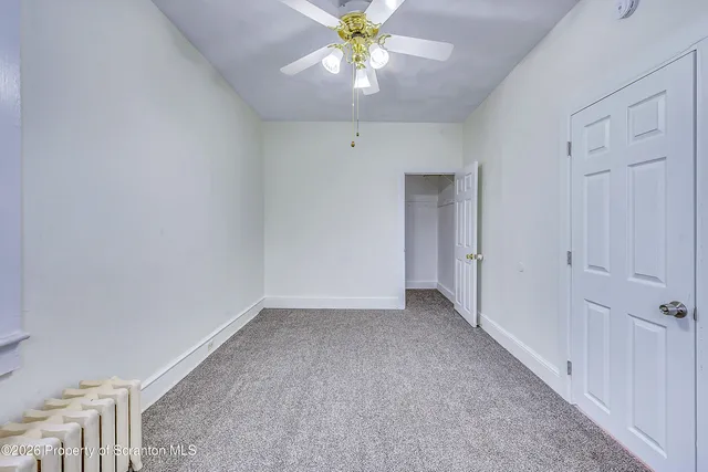 a view of an empty room and chandelier fan