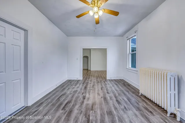a view of an empty room with window and wooden floor
