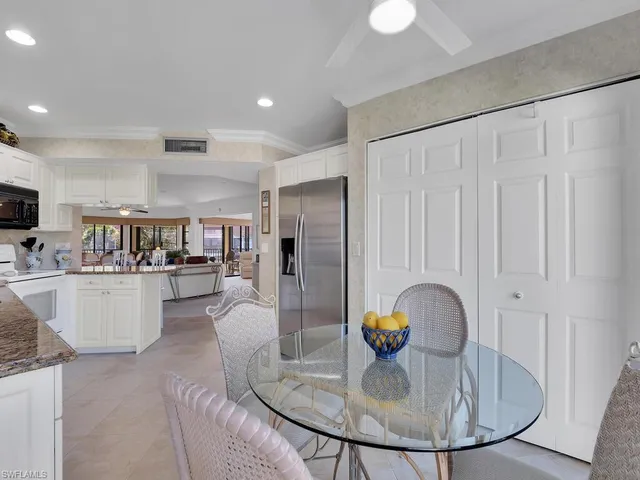 a kitchen with stainless steel appliances granite countertop a refrigerator a stove a microwave oven a dining table and chairs with wooden floor