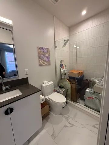 a bathroom with a granite countertop toilet sink and mirror