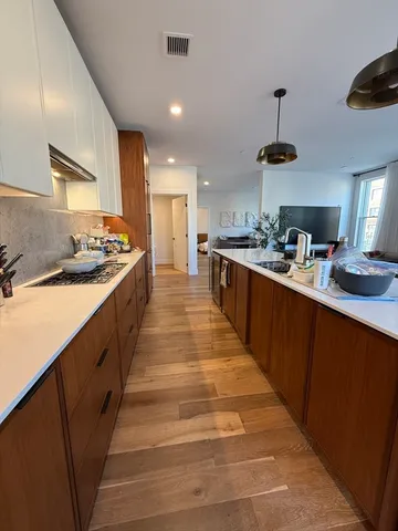 a large kitchen with stainless steel appliances a sink stove and cabinets