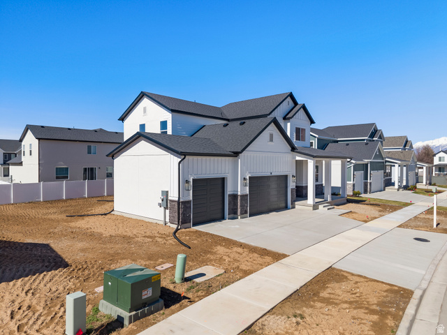 58 South Crimson Way, Unit 306 Mapleton, UT 84664 - Photo 2 of 24 Contemporary two-story residence featuring a two-car garage, board and batten siding, dark stone accent details, and a covered porch entry