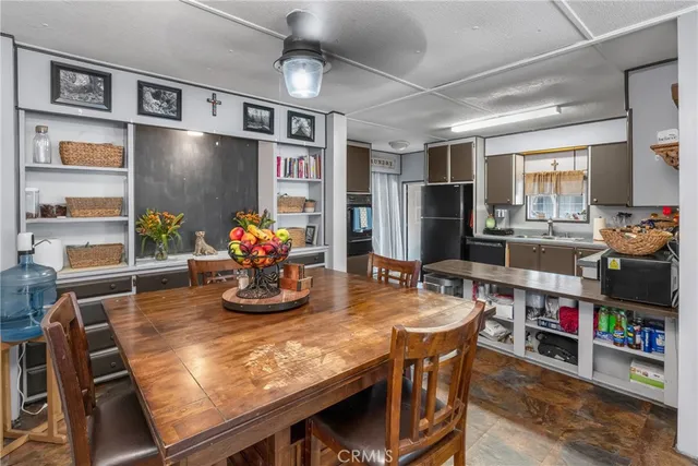 a kitchen with stainless steel appliances granite countertop a dining table chairs and a refrigerator