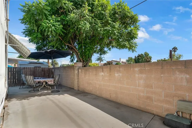 a backyard of a house with table and chairs under an umbrella