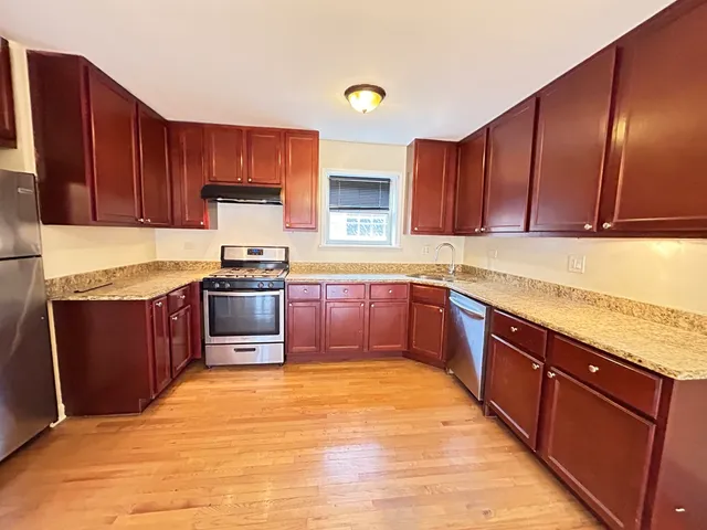 a kitchen with stainless steel appliances granite countertop wooden cabinets a stove top oven a sink and dishwasher