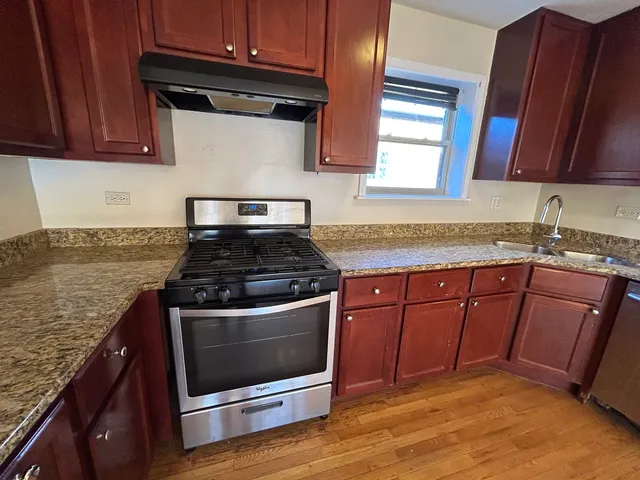 a kitchen with granite countertop wooden cabinets and a stove top oven