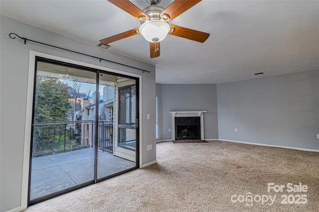 a view of an empty room with chandelier fan and fire place