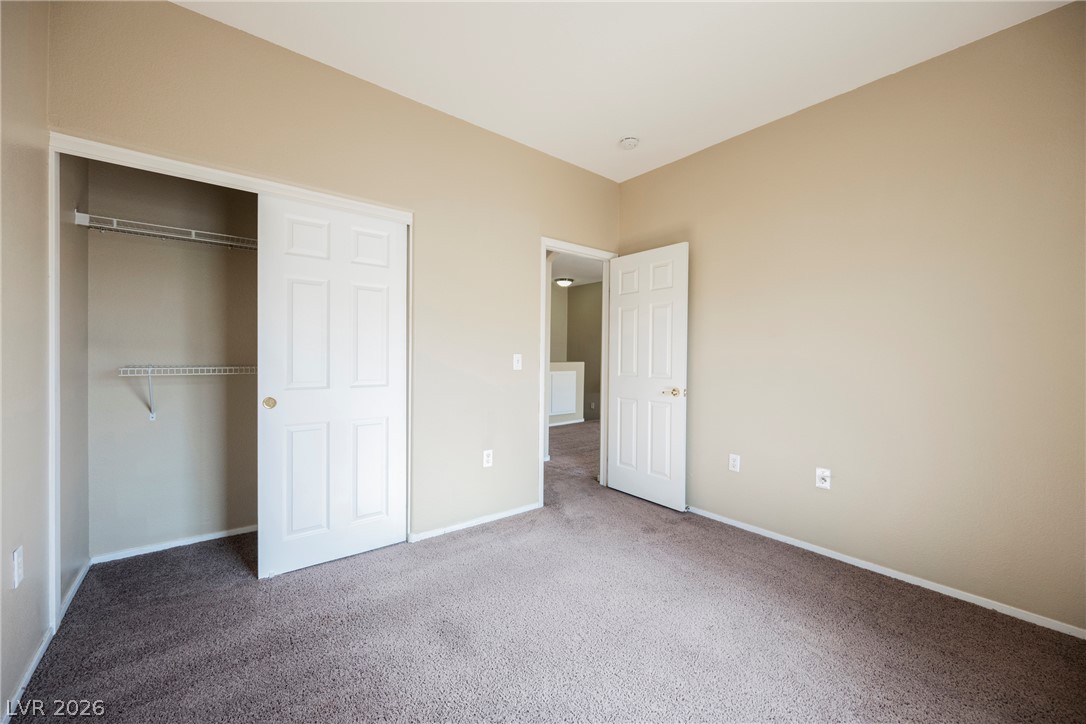 6320 Snap Ridge Street, Unit 201 North Las Vegas, NV 89081 - Photo 33 of 56 An open closet and entryway enhance the neutral bedroom's appeal.