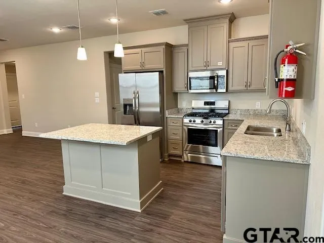 a kitchen with stainless steel appliances granite countertop a refrigerator a stove and a sink