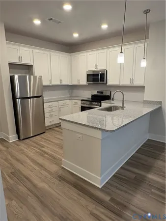 a kitchen with stainless steel appliances granite countertop a sink a stove a refrigerator a center island with wooden floor