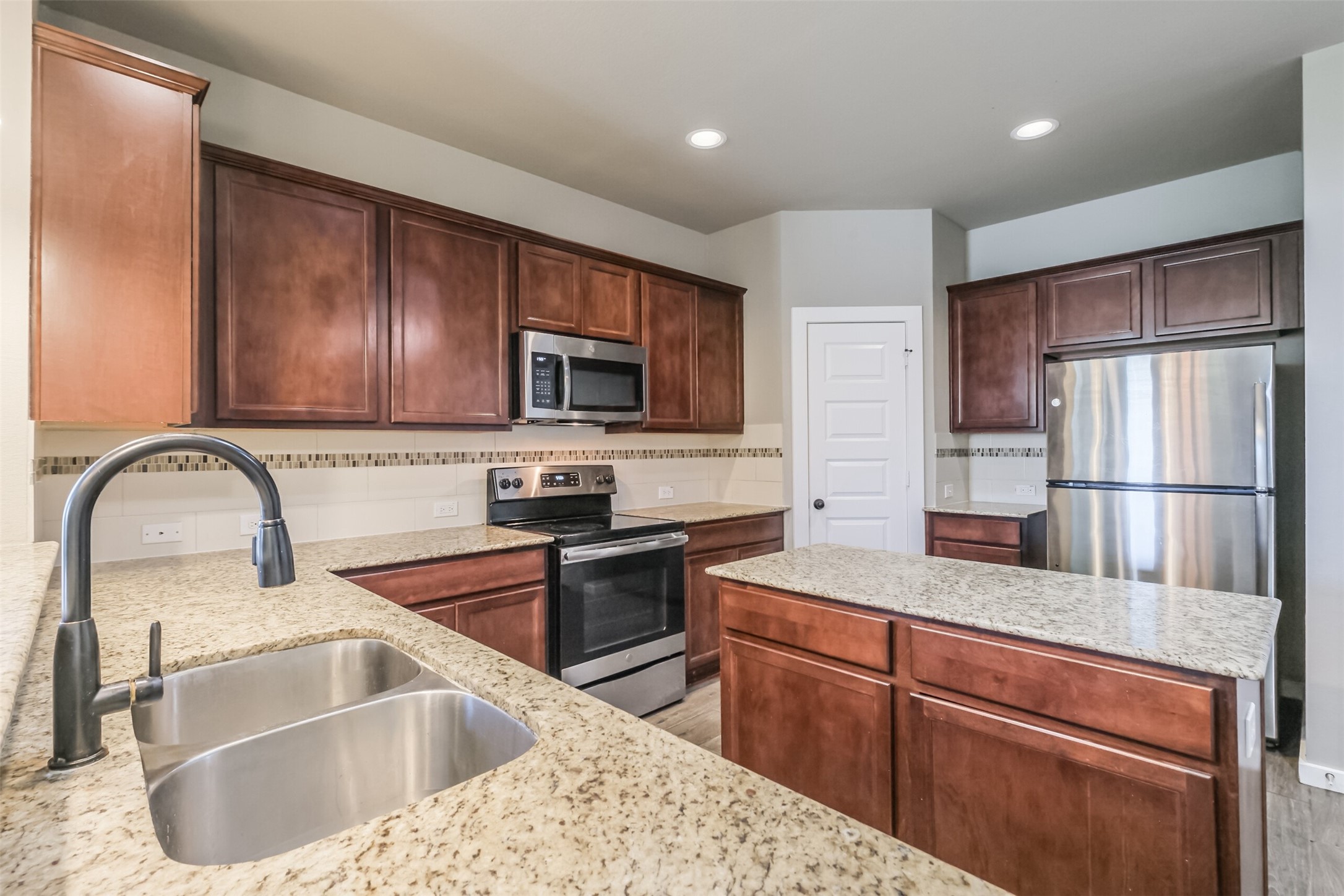 121 Wickersham, Unit A Conroe, TX 77304 - Photo 6 of 37 a kitchen with stainless steel appliances granite countertop a sink refrigerator and microwave