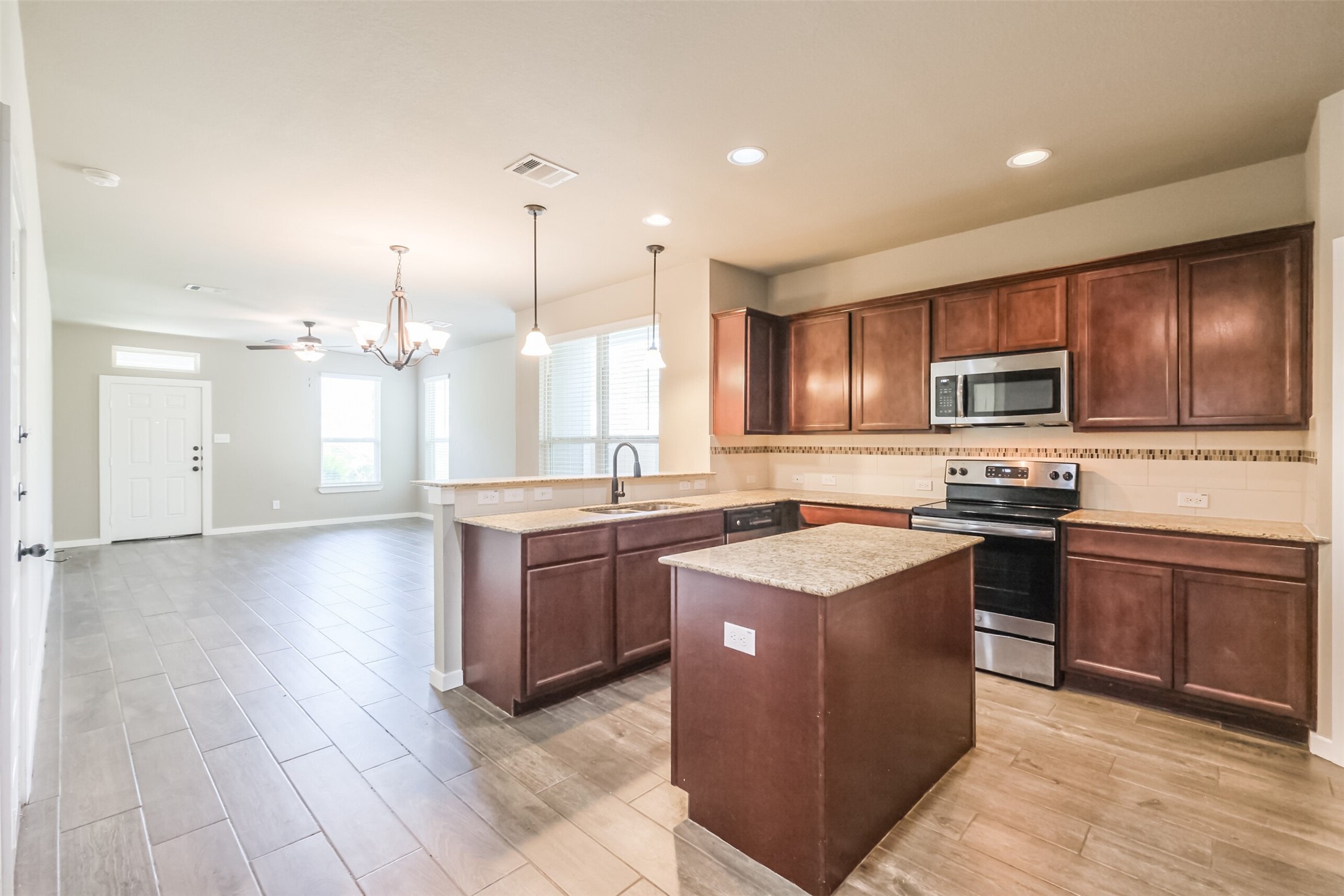 121 Wickersham, Unit A Conroe, TX 77304 - Photo 7 of 37 a kitchen with stainless steel appliances granite countertop a stove top oven a sink dishwasher a refrigerator and a oven with wooden floor