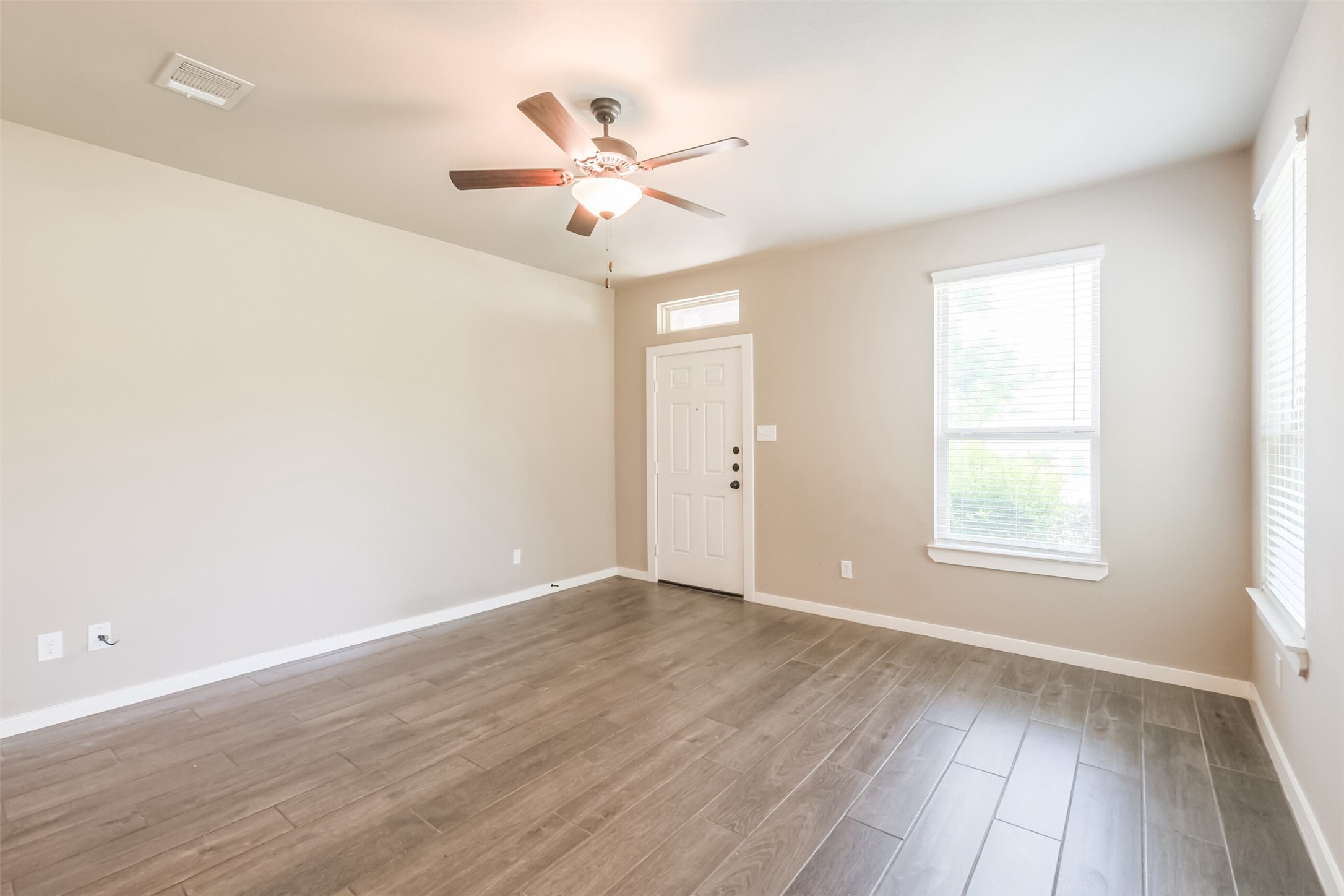 121 Wickersham, Unit A Conroe, TX 77304 - Photo 10 of 37 an empty room with wooden floor fan and windows