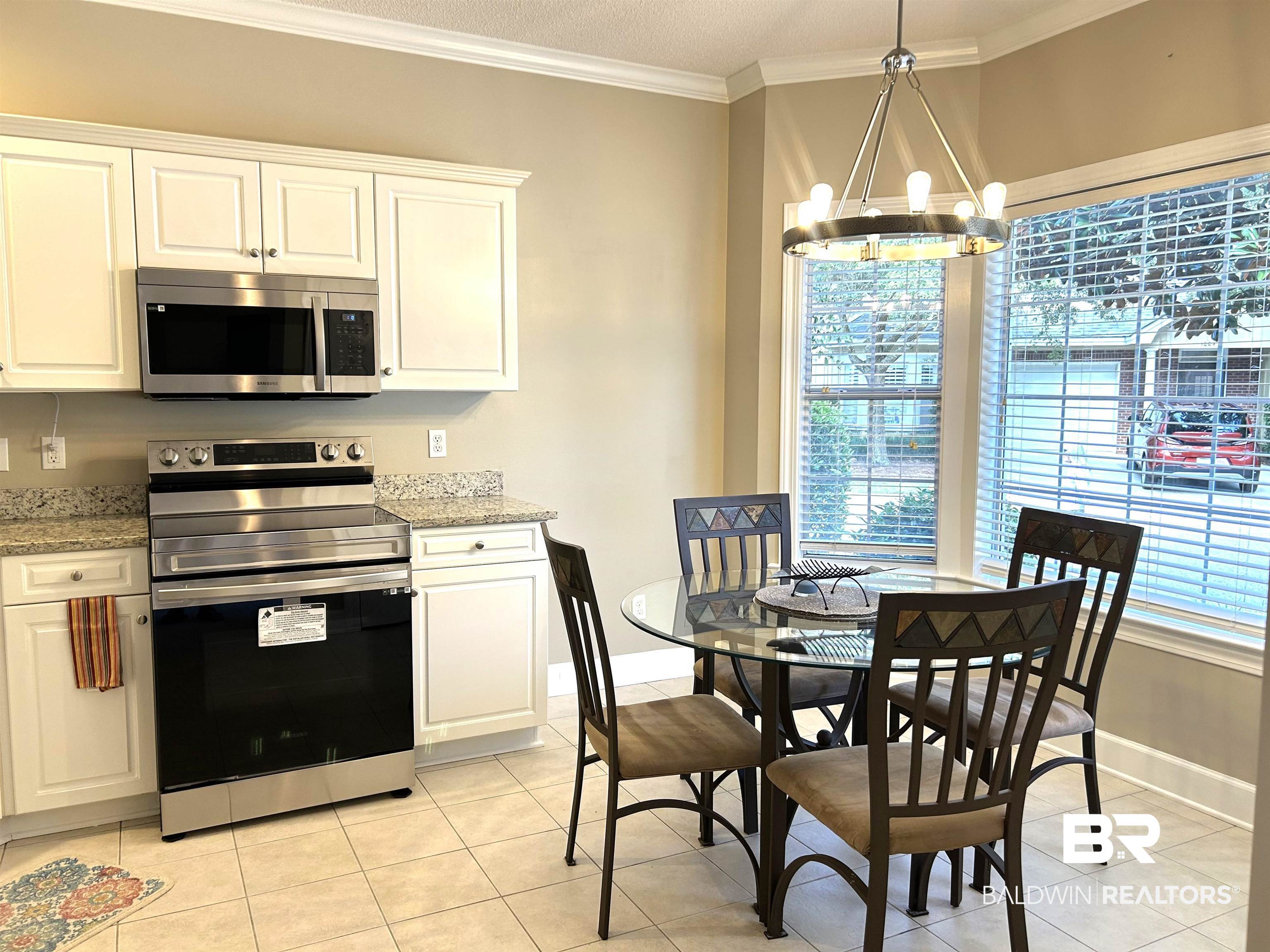 430 West Fort Morgan Road, Unit 404 Gulf Shores, AL 36542 - Photo 11 of 31 Kitchen with appliances with stainless steel finishes, light stone counters, white cabinetry, a chandelier, and ornamental molding