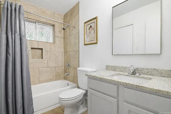 a bathroom with a granite countertop sink a toilet and shower