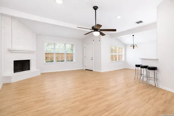 a view of an empty room with window and wooden floor
