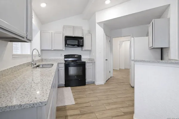 a kitchen with granite countertop a sink stainless steel appliances and cabinets