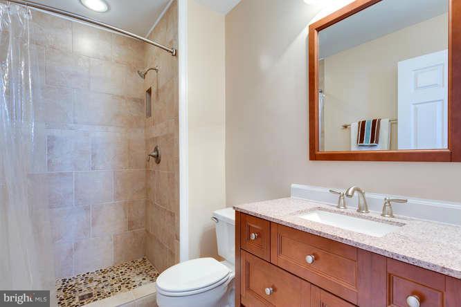 21053 Cornerpost Square Ashburn, VA 20147 - Photo 19 of 30 a bathroom with a granite countertop sink toilet a shower and a mirror