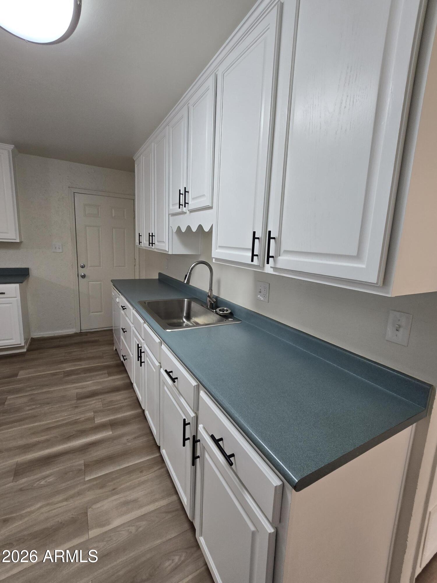 6512 North 41st Avenue Phoenix, AZ 85019 - Photo 12 of 24 a kitchen with granite countertop a sink and dishwasher a stove top oven with wooden floor
