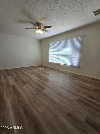 an empty room with wooden floor chandelier fan and windows