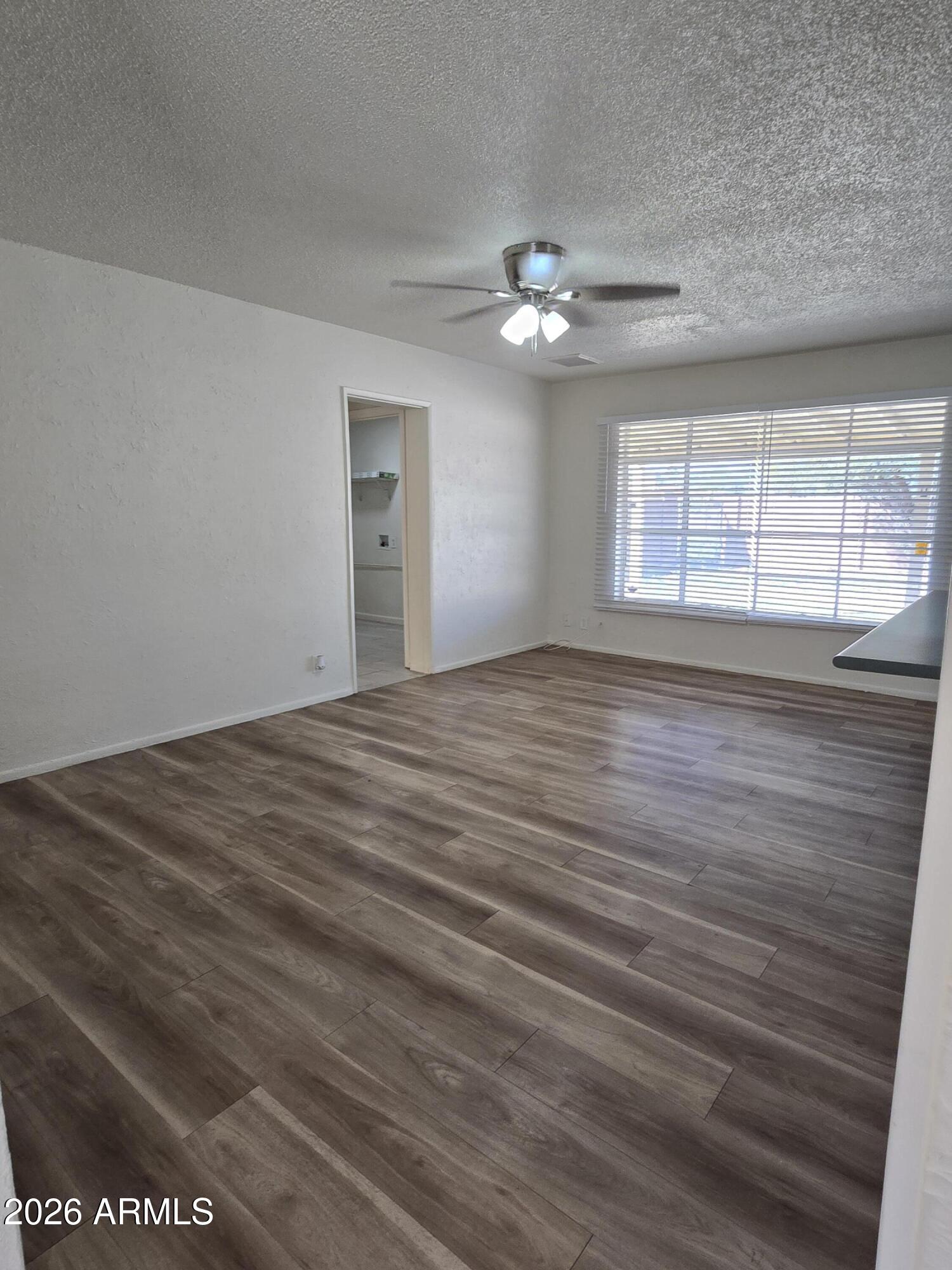 6512 North 41st Avenue Phoenix, AZ 85019 - Photo 5 of 24 a view of an empty room with wooden floor and a window