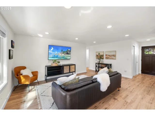 a living room with furniture two window and a flat screen tv