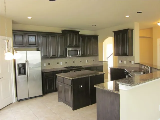 a kitchen with a refrigerator sink and cabinets