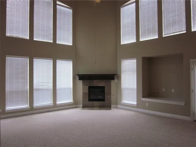 an empty room with windows and fireplace